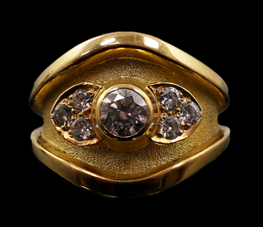 A 1990's part textured 18ct gold and collet set single stone diamond ring by Leo De Vroomen, with six stone diamond set shoulders, retailed by Boodle & Dunthorne